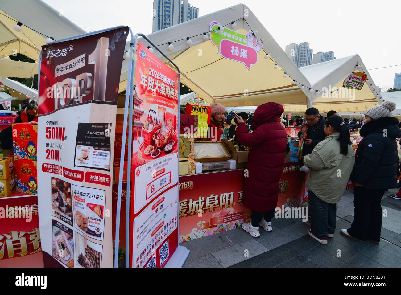 Shoppers browse and take photos at a snack stall displaying promotional ...