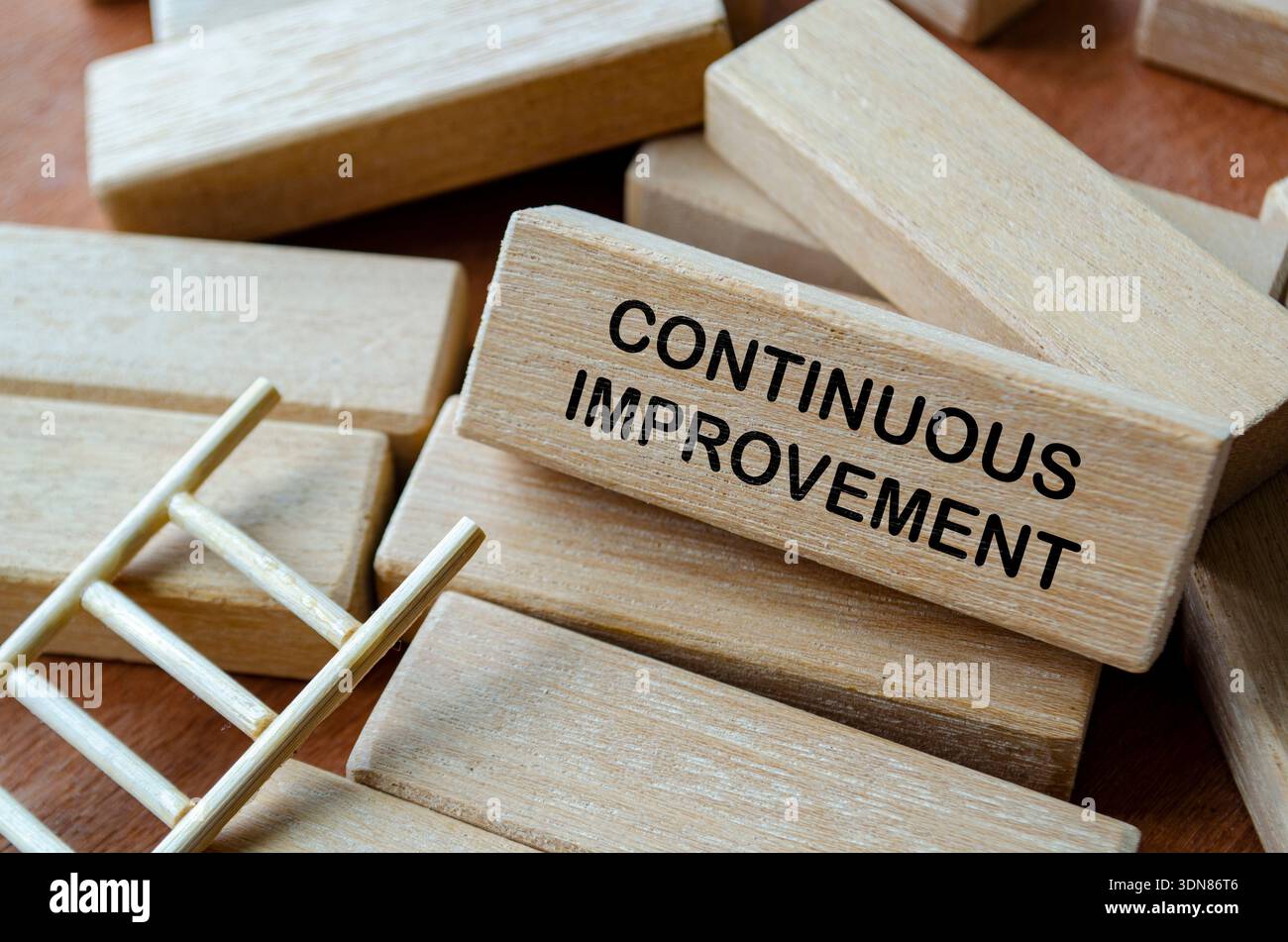 CONTINUOUS IMPROVEMENT text on wooden blocks on office desk representing ongoing process optimization and business efficiency. Stock Photo