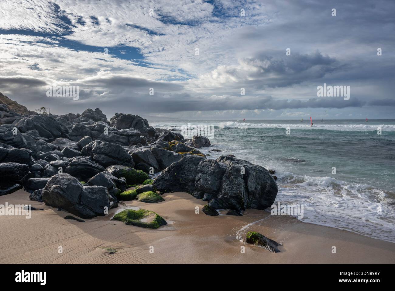 Rocky beach with dynamic waves under a cloudy, dramatic sky. Paia, Hawaii, USA Stock Photo