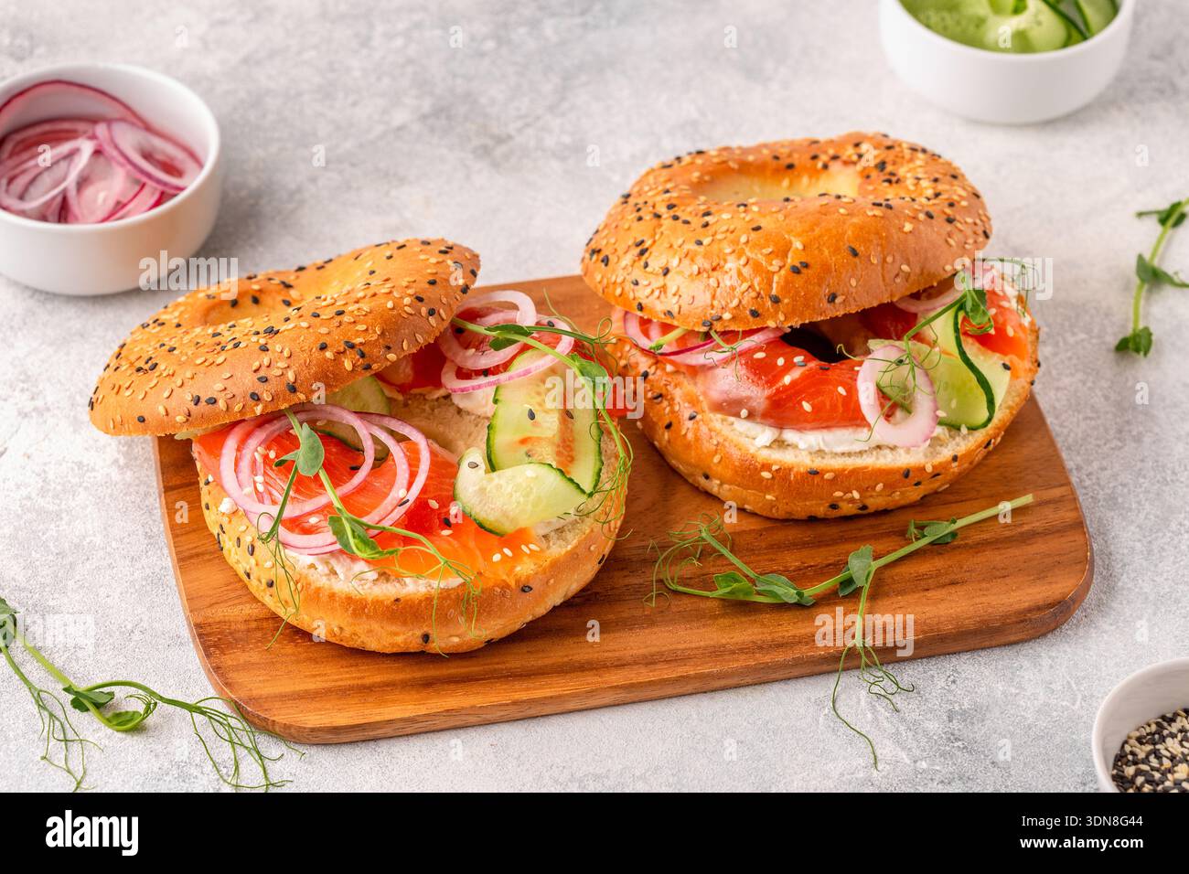 Bagel and salmon lox with cream cheese, cucumbers, onions and microgreens. Stock Photo