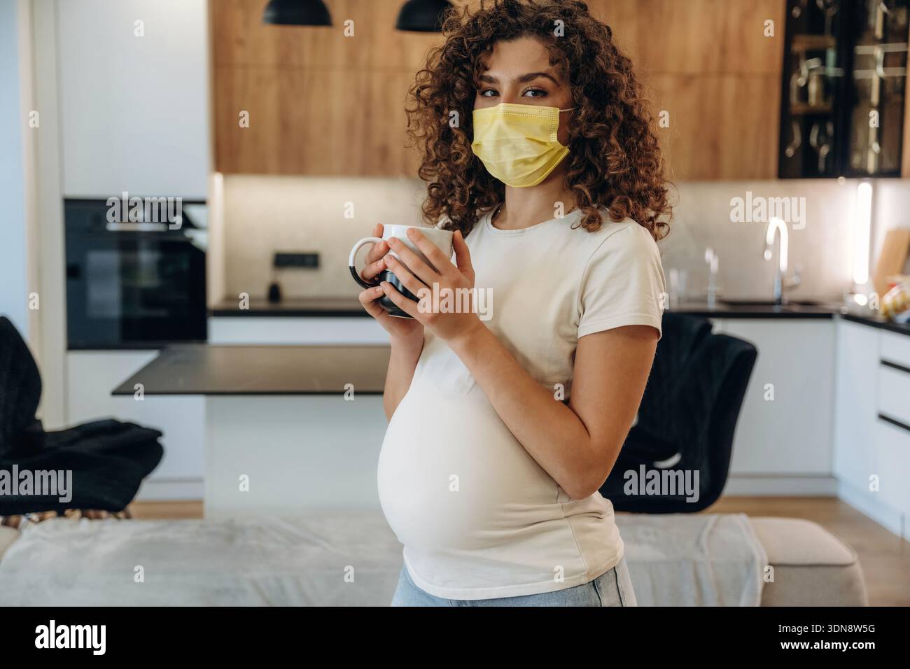 Pregnant woman at home, with belly and enjoying a peaceful moment in a modern kitchen. Stock Photo