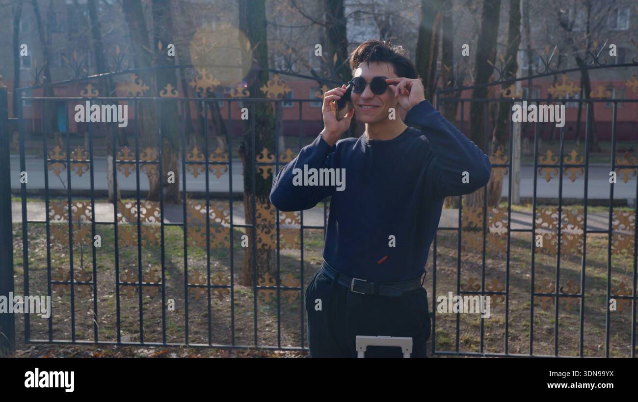 Handsome man standing in park and using smartphone Stock Photo