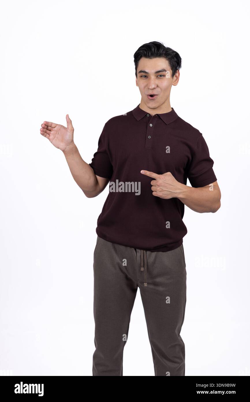 Smiling man in brown shirt pointing aside in studio Stock Photo