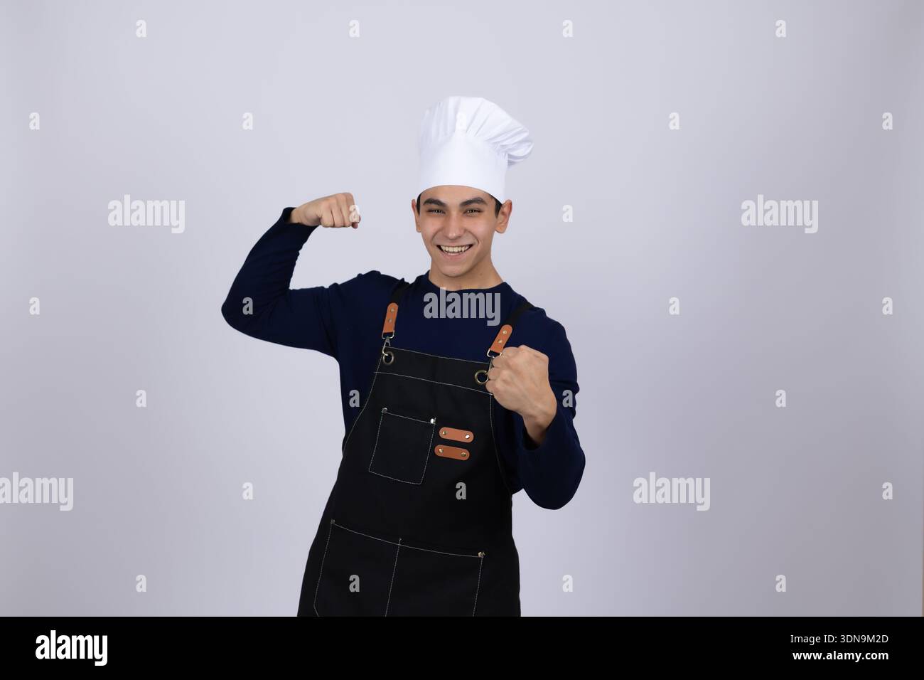 Happy chef in white uniform flexing his muscles Stock Photo