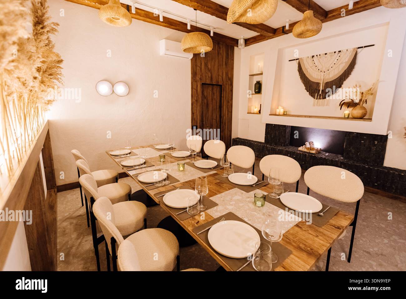 Cozy boho private dining room with long table setting and warm lighting Stock Photo