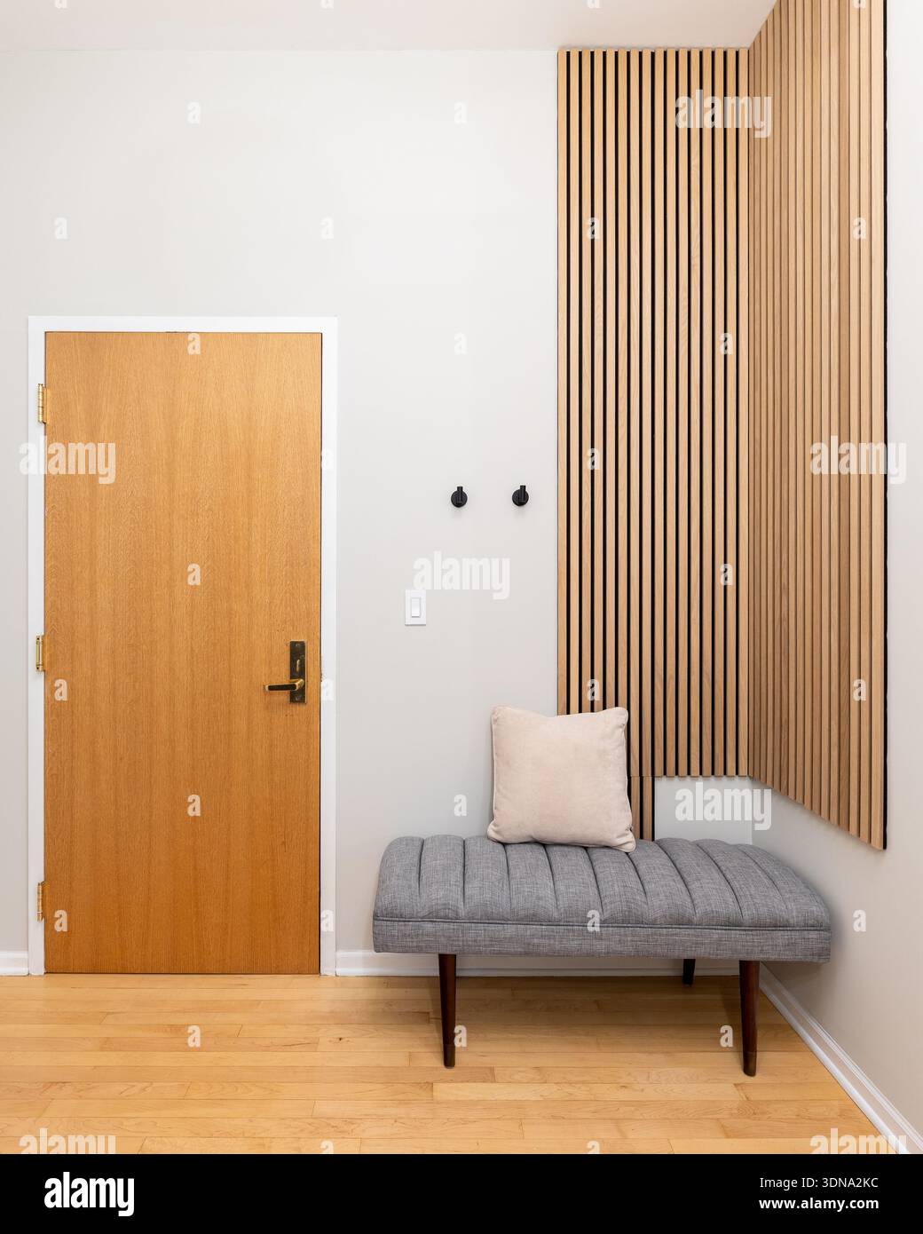 A modern entryway featuring a natural wood door, a textured gray bench ...