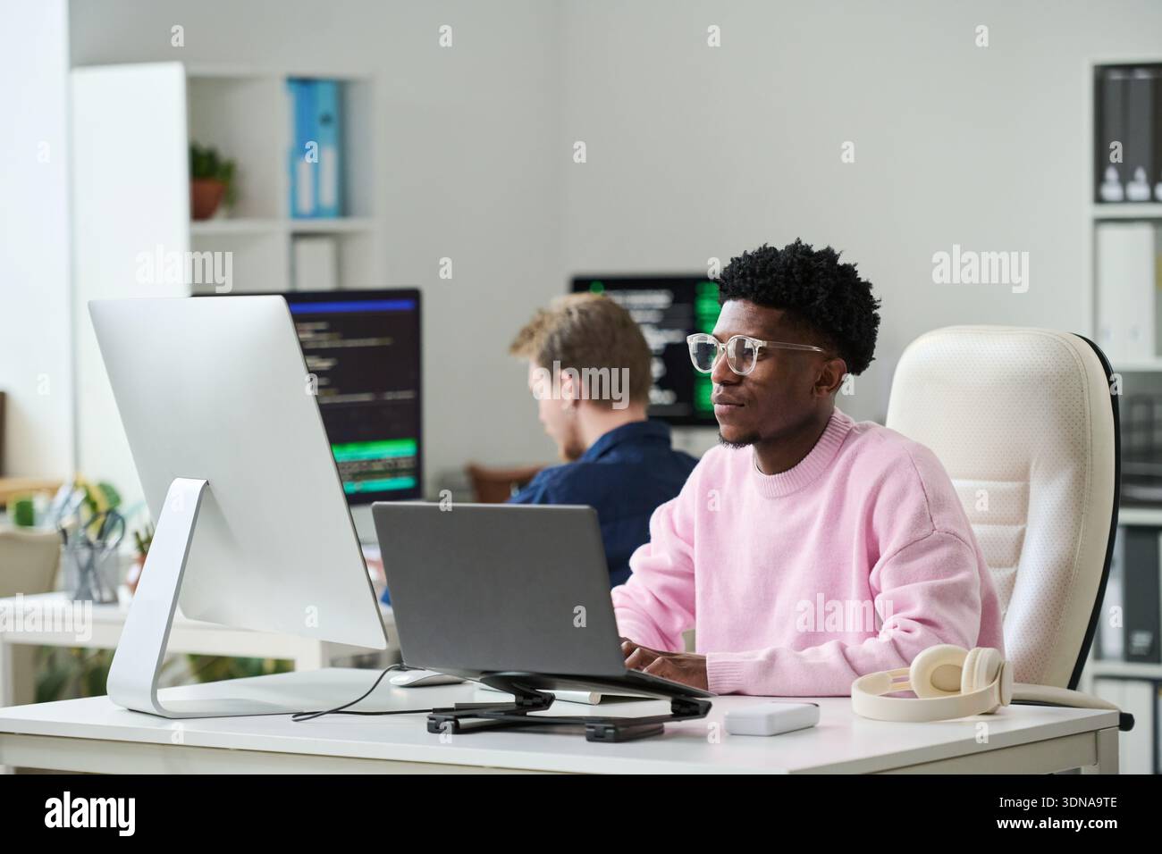 Young Black Man Concentrating on Software Engineering Tasks in Office Stock Photo