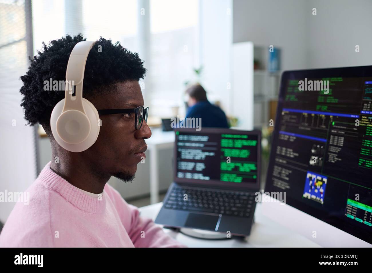 Young Black Man Wearing Headphones Working on Computer Programming Code Stock Photo