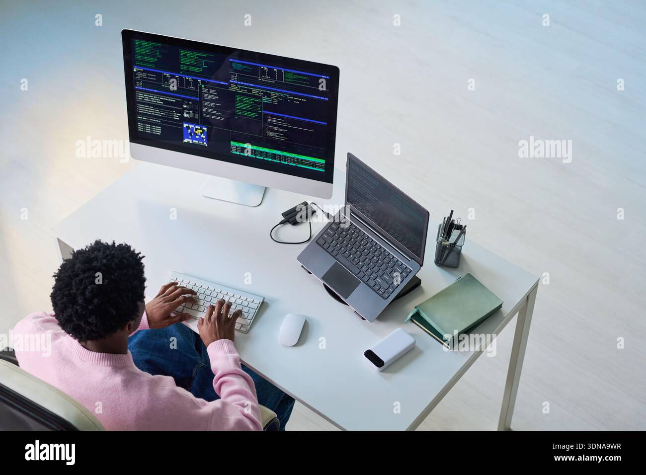 Young Black Man Coding on Computer and Laptop at Desk Workspace Stock Photo