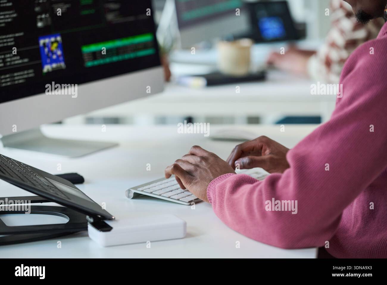 Young Black Man Typing on Keyboard While Working with Computer Monitor Stock Photo