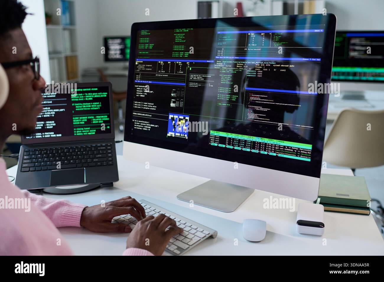 Young Black Man Coding Software on Desktop Computer in Office Stock Photo