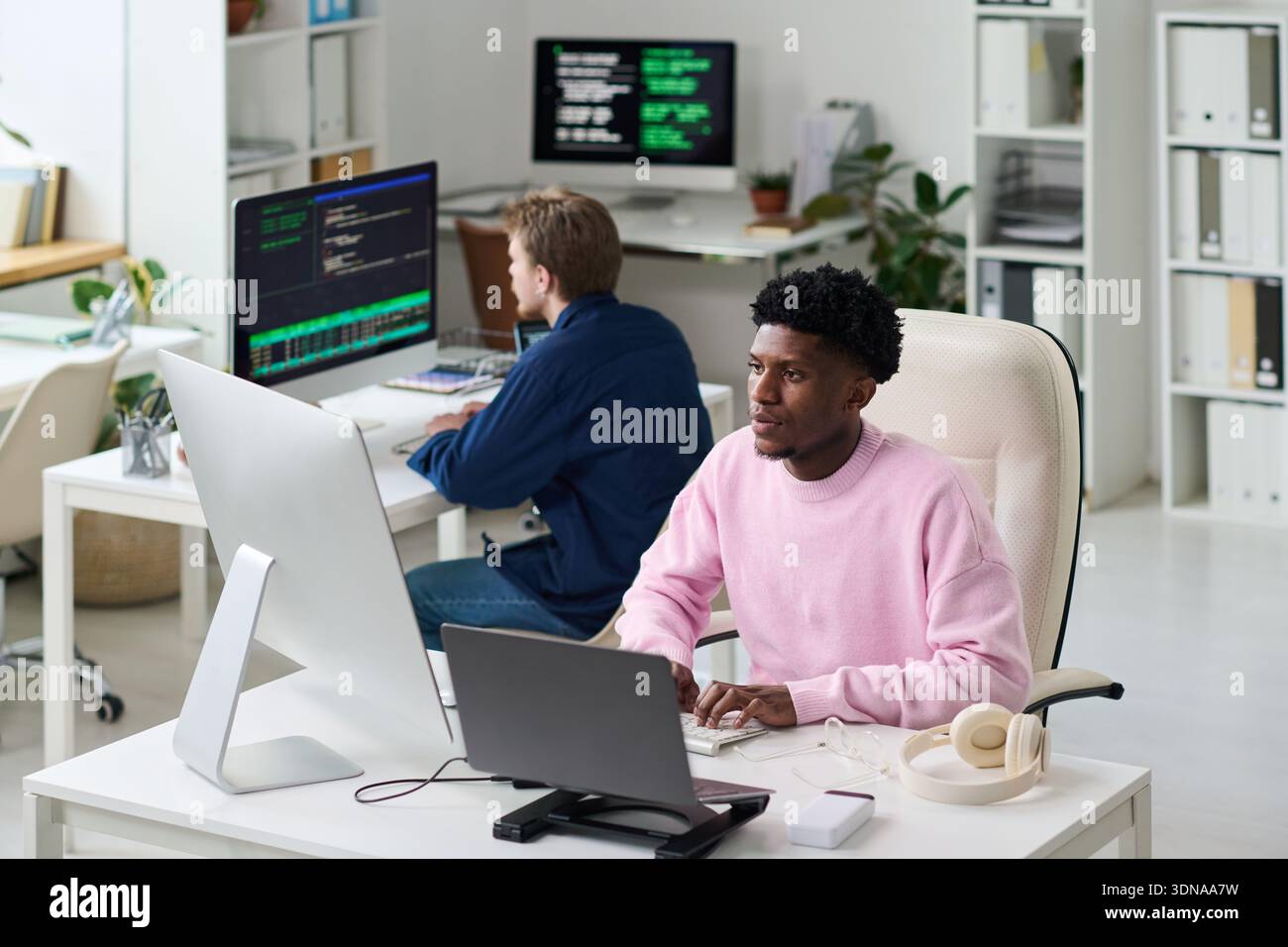 Young Black Man Collaborating with Colleague on Software Development Stock Photo