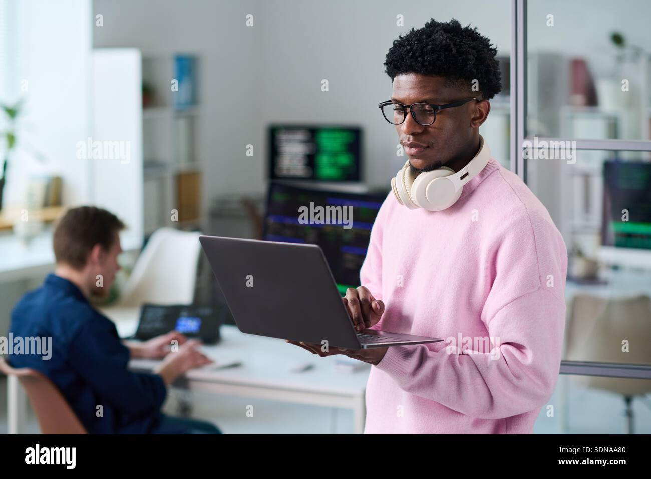 Young Black Man Using Laptop Computer in Office Workspace Stock Photo