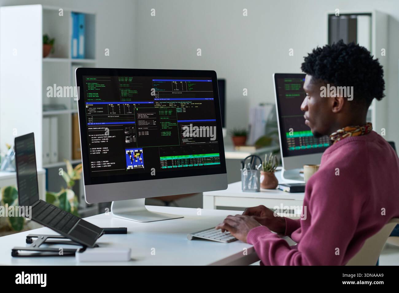 Young Black Man Analyzing Programming Code on Desktop Computer Screen Stock Photo