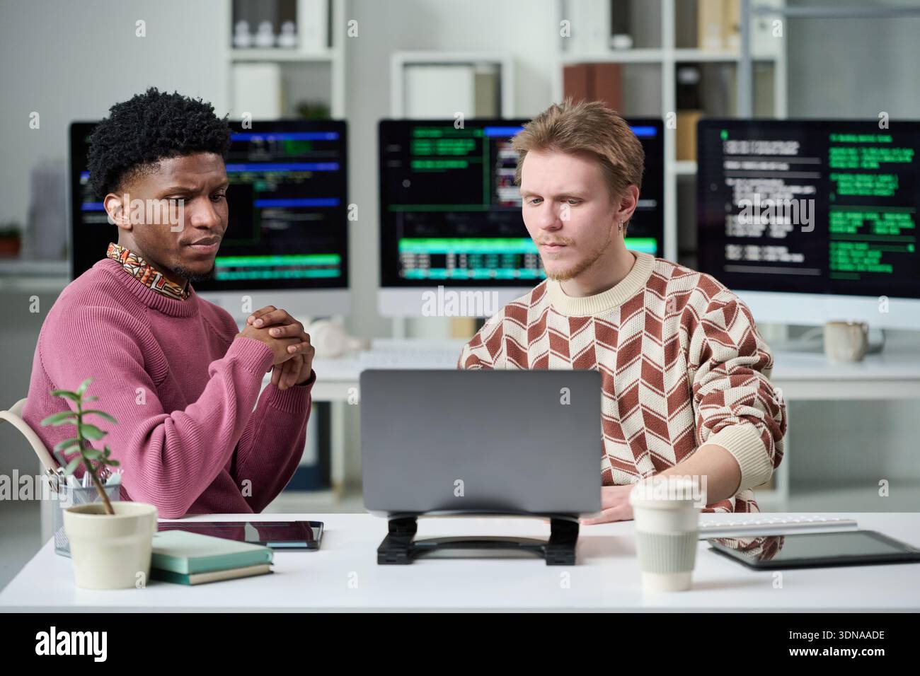 Young Man and Young Black Man Collaborating on Software Development Stock Photo