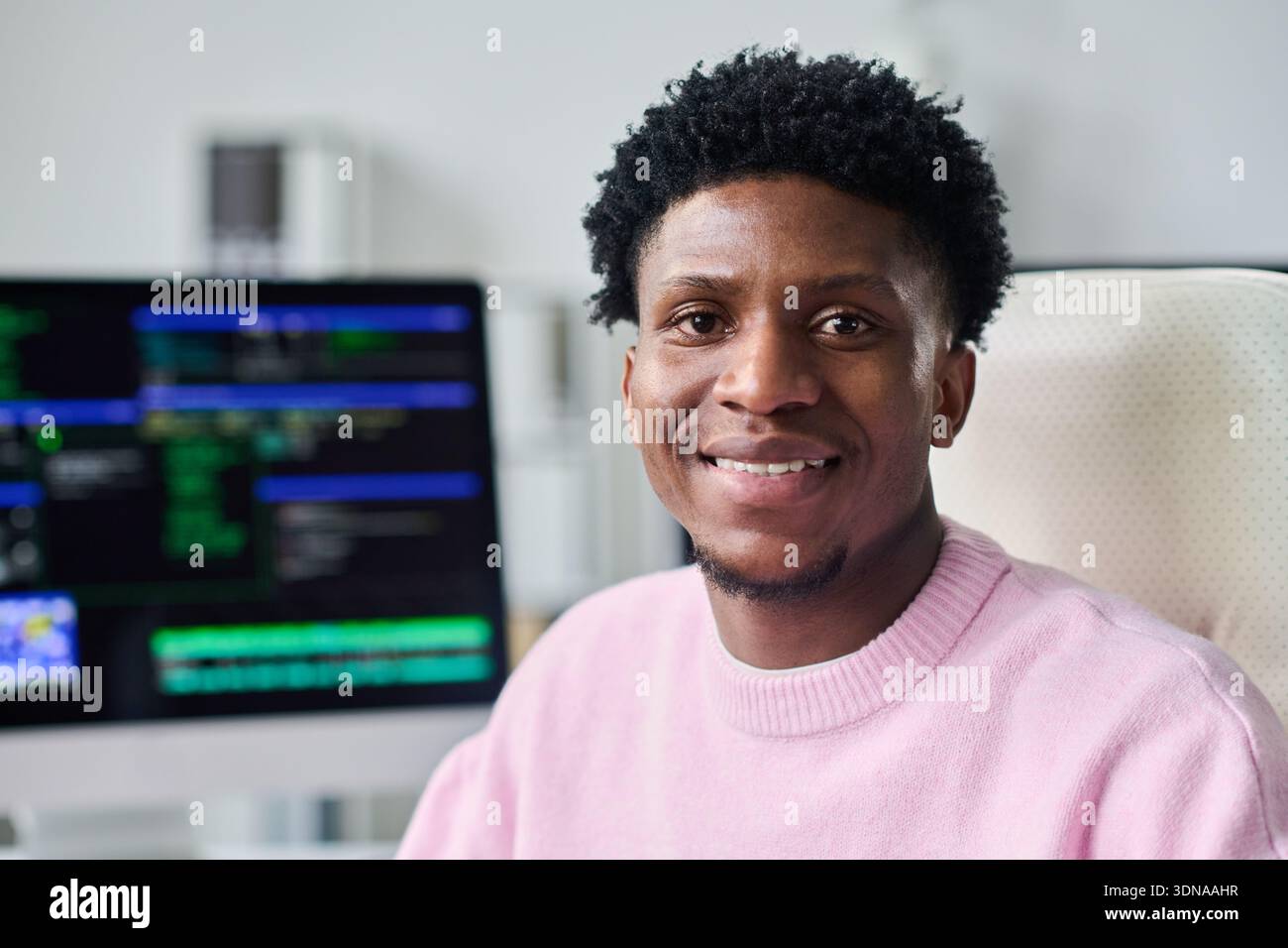Portrait of Young Black Man Smiling While Working at Computer Desk Stock Photo