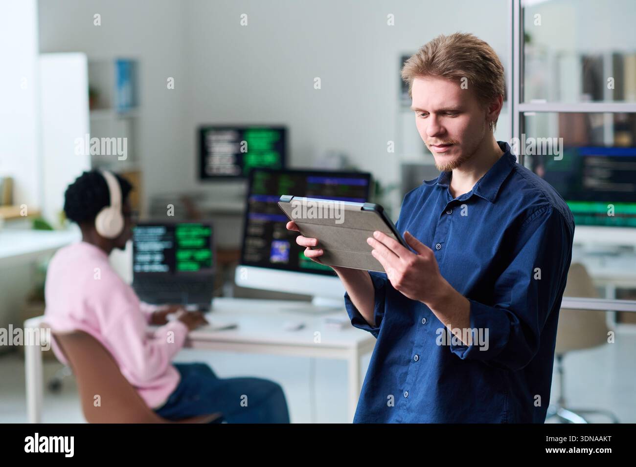 Young Man Using Digital Tablet in Office Workspace Stock Photo