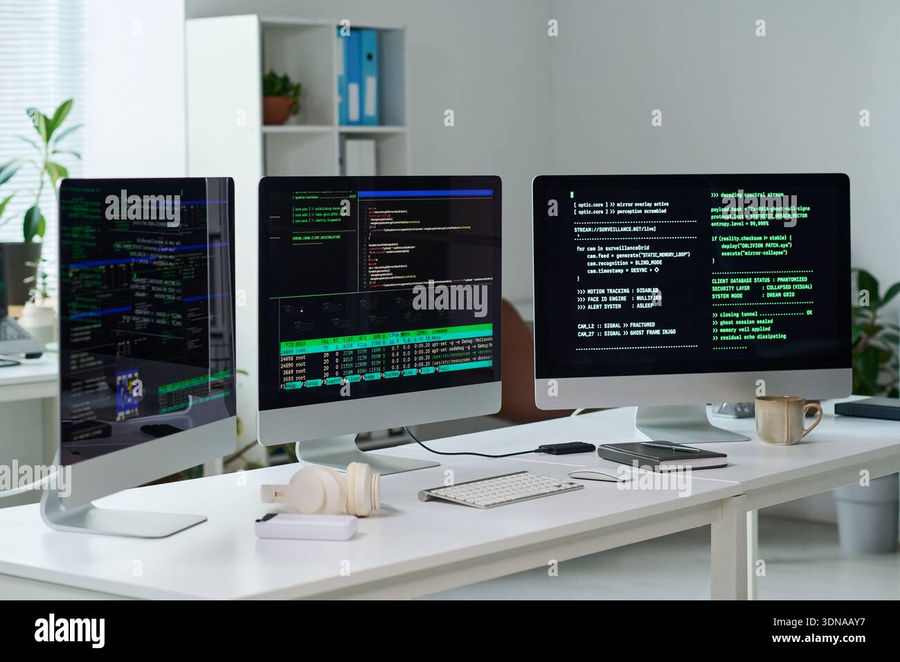Three Computer Monitors Displaying Programming Code in Office Setting Stock Photo