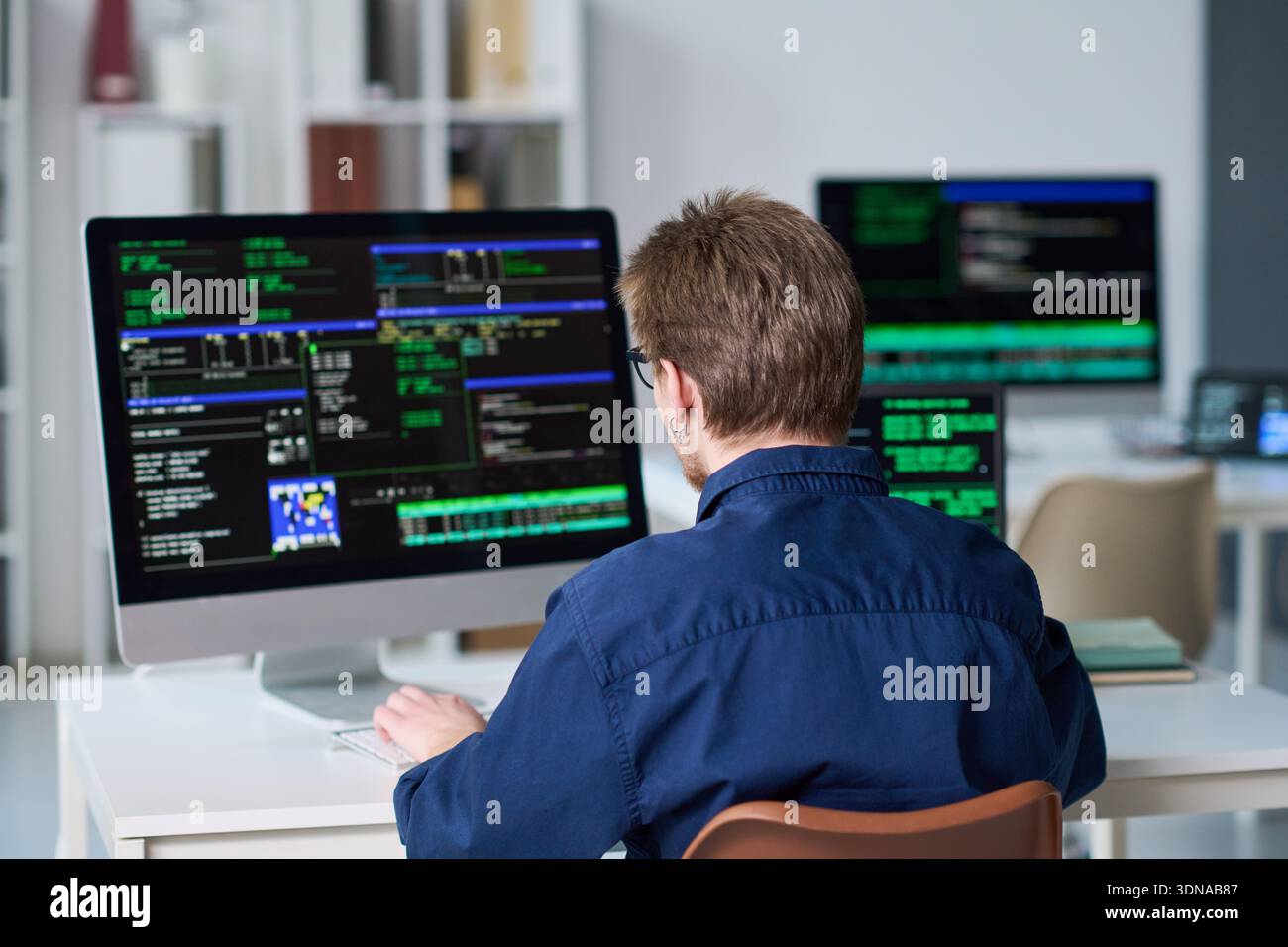 Young Man Working on Computer with Programming Code Displayed Stock Photo
