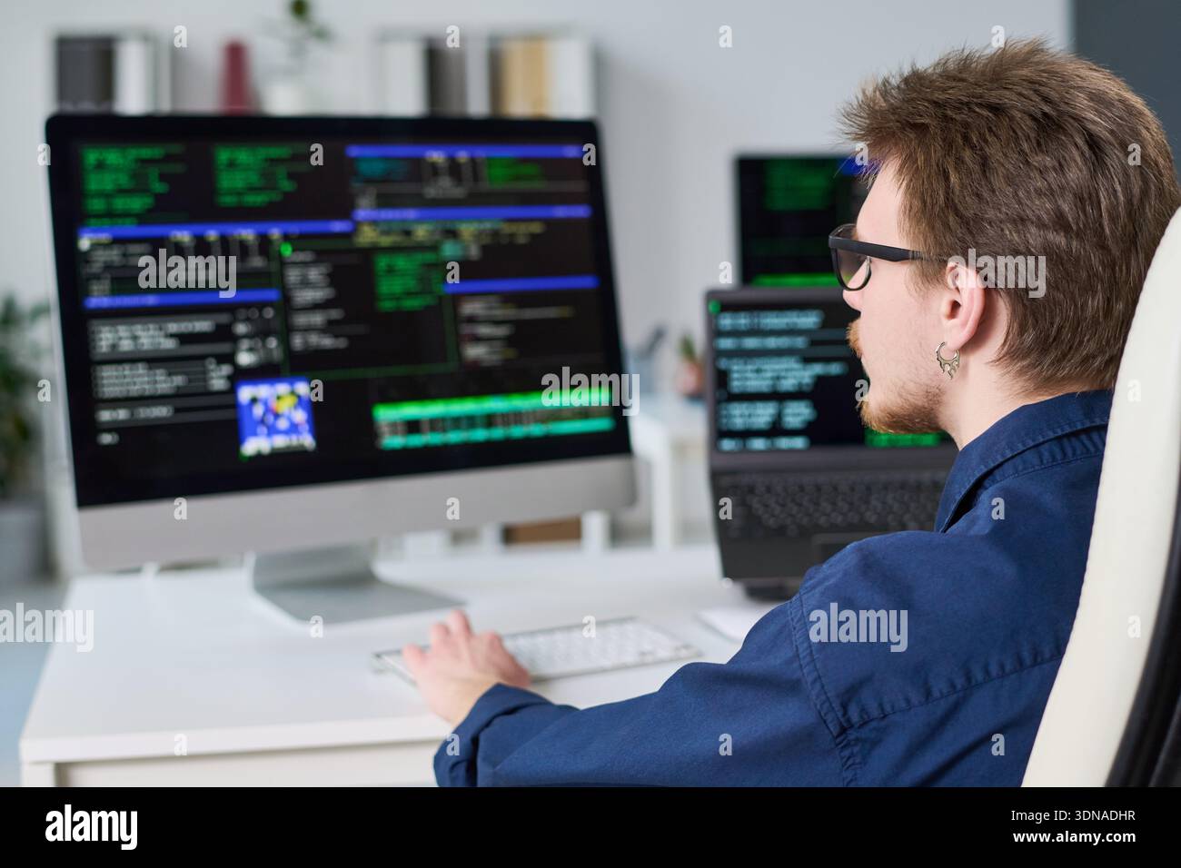 Young Man Writing Code on Computer in Office Setting Stock Photo