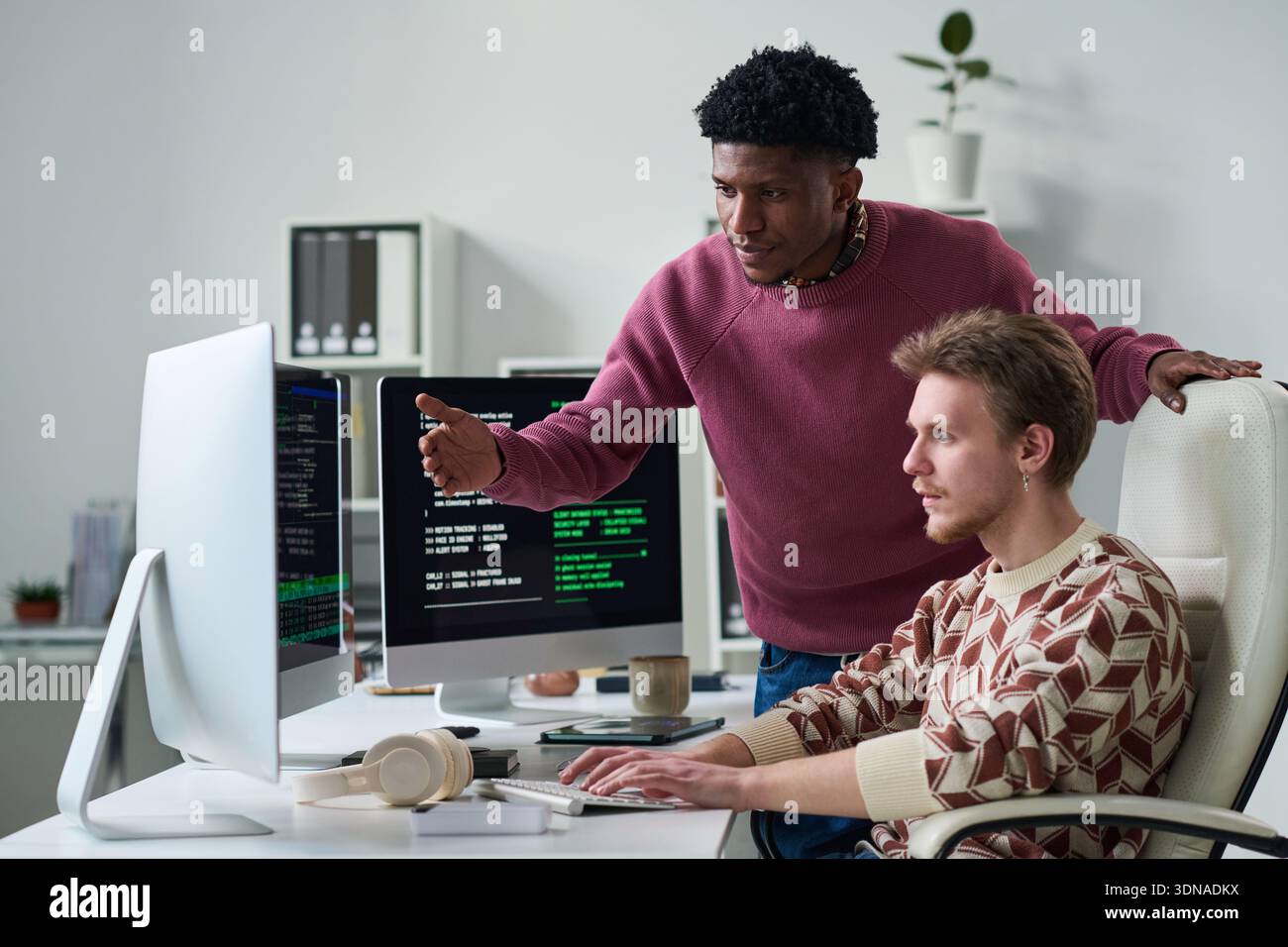 Young Black Man Explaining Programming Code to Young Man Stock Photo