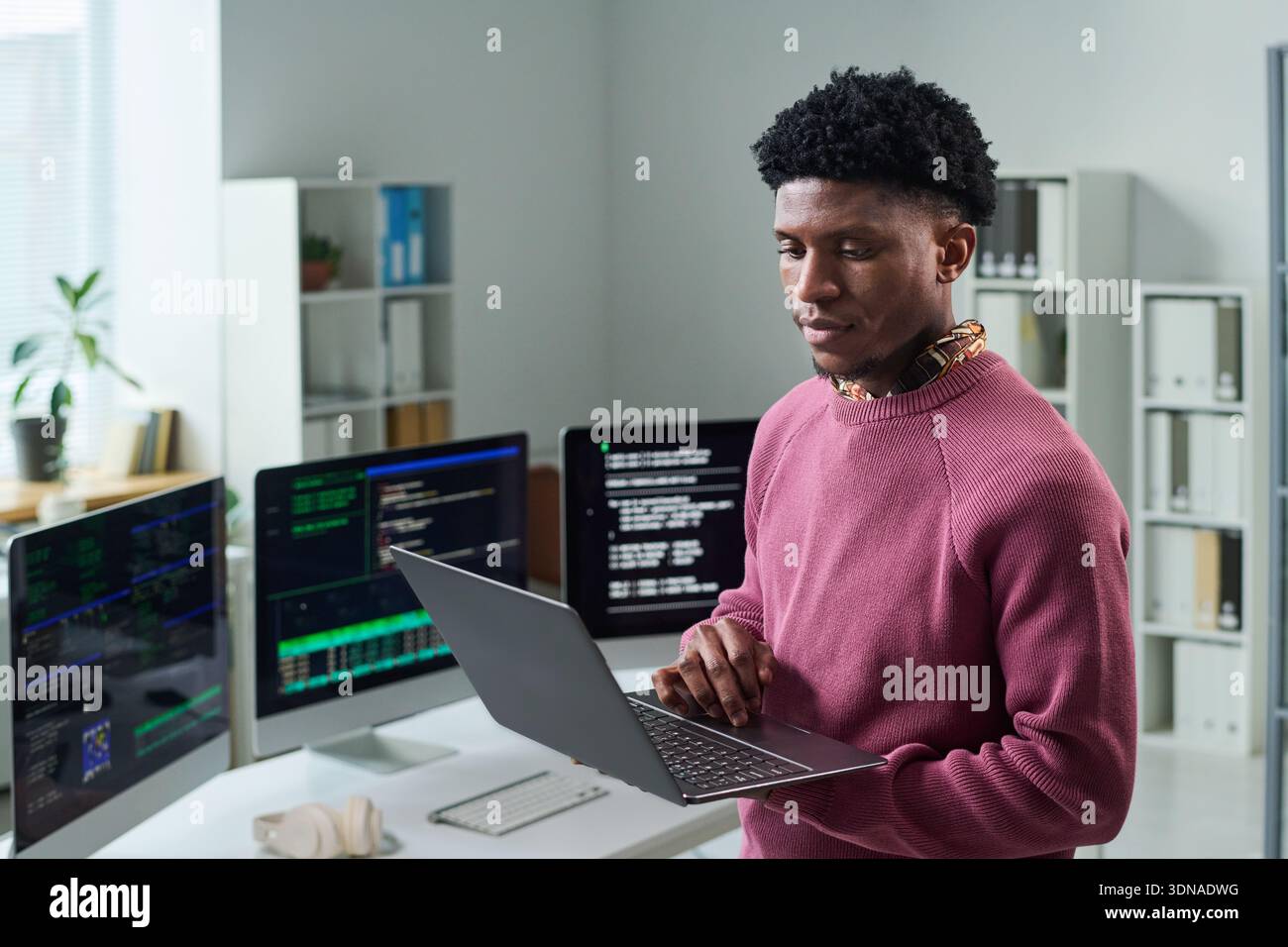 Young Black Man Using Laptop While Working in Office Environment Stock Photo