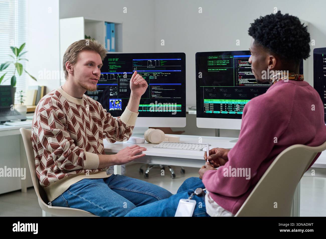 Young Man Explaining Programming Concepts to Young Black Man Stock Photo