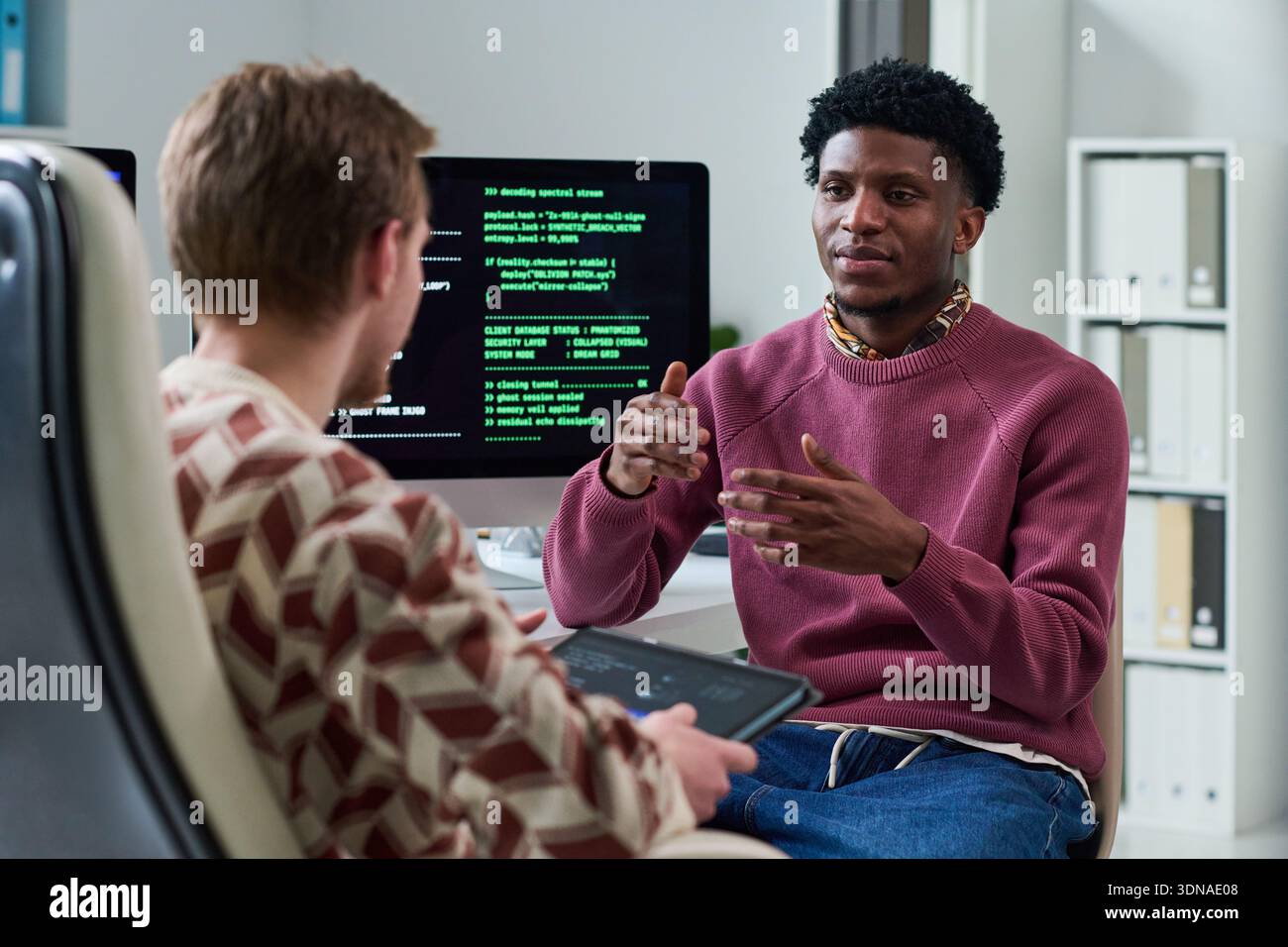 Young Black Man Explaining Software Concepts to Colleague Stock Photo