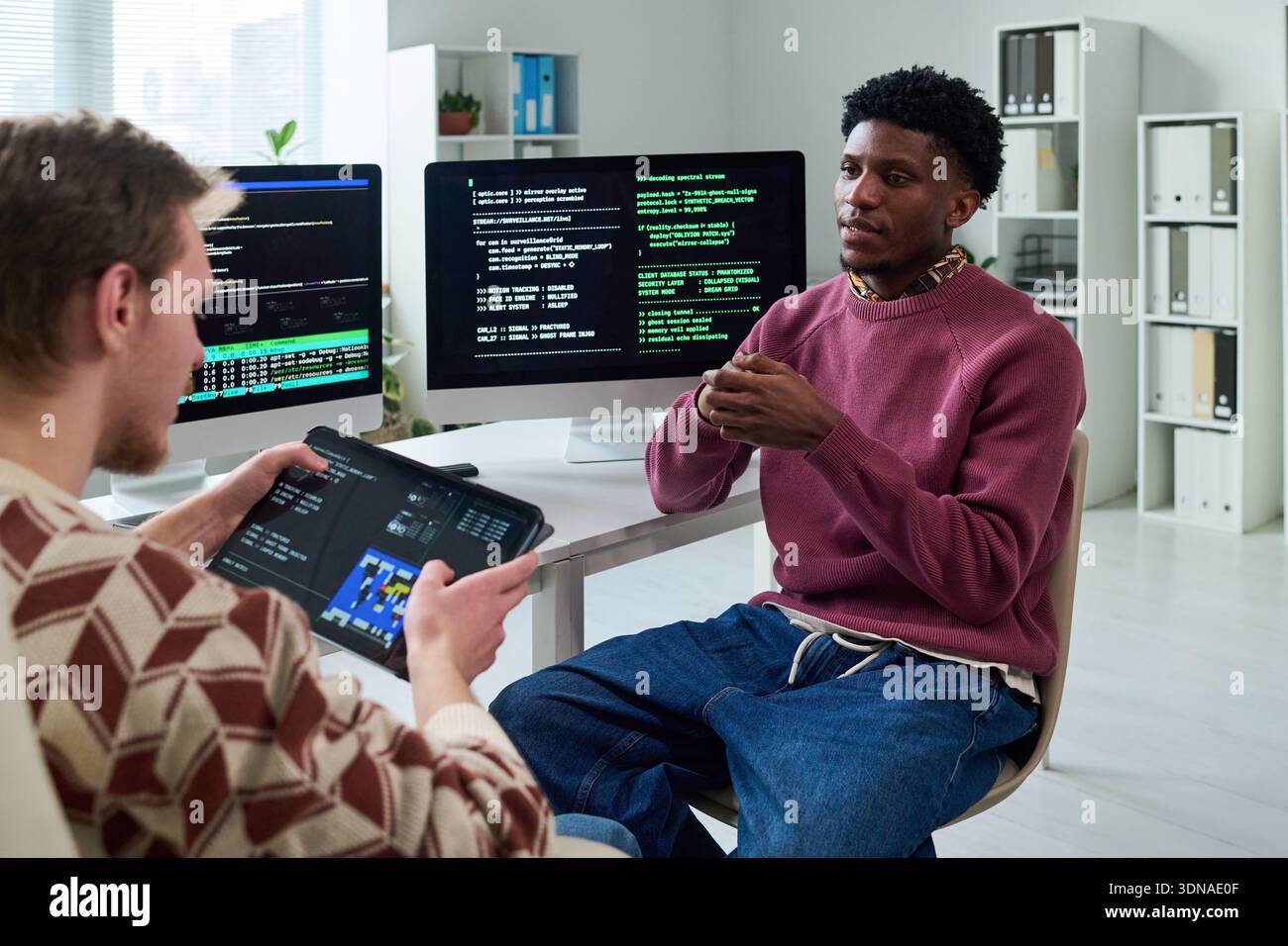 Young Black Man Explaining Programming Concepts to Colleague Stock Photo