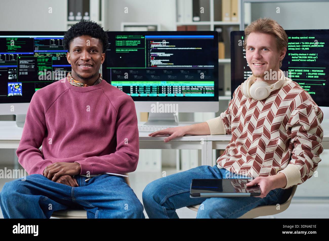 Young Multiethnic Men Collaborating in Office with Computer Screens Stock Photo
