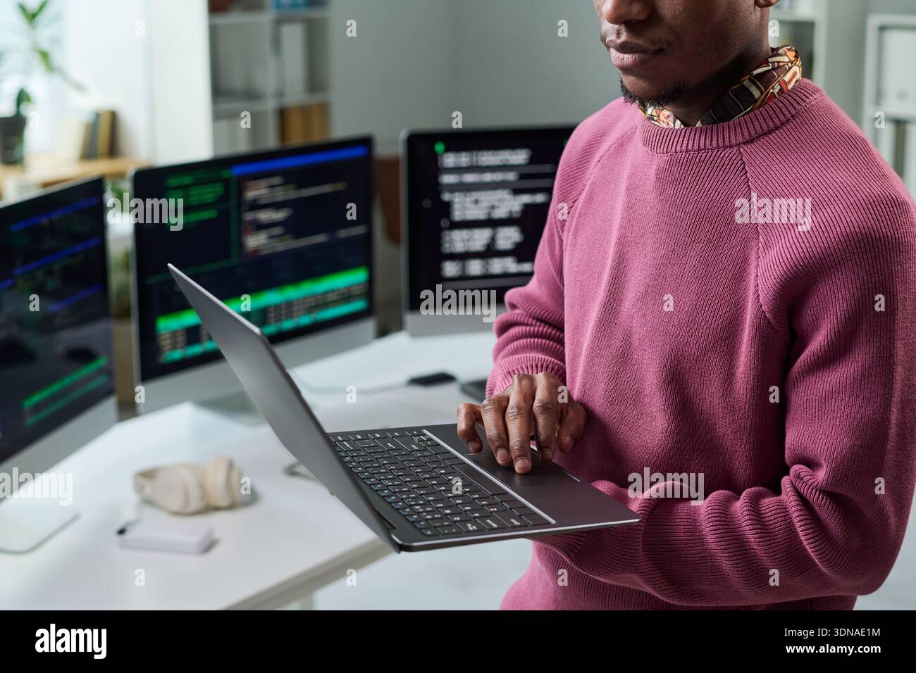 Young Black Man Reviewing Software Code on Laptop in Technology Office Stock Photo