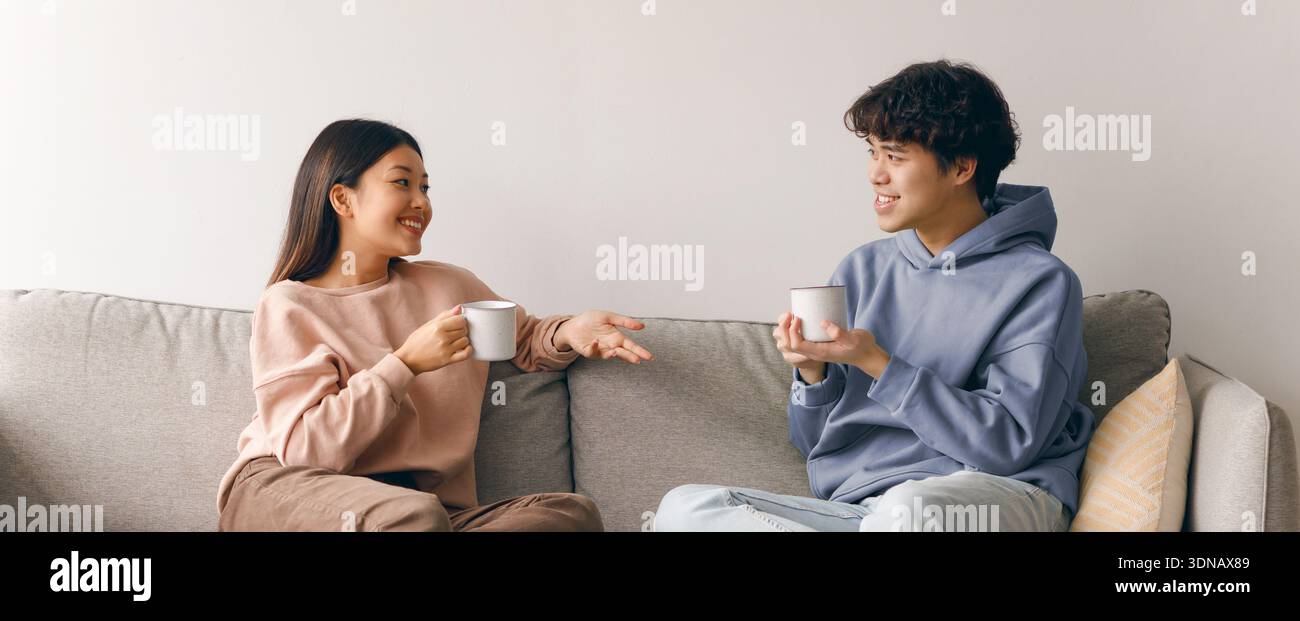 Young Couple Enjoys Conversation Over Coffee on a Comfortable Sofa During the Afternoon Stock Photo