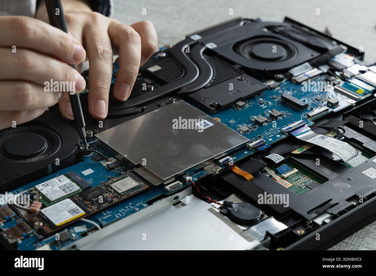 Hands are fixing a laptop in a workspace. Tools are used to open the ...