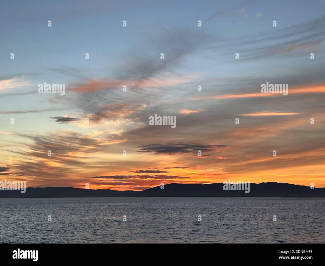Dark clouds streak an orange-to-blue sky above the SF Peninsula - Smartphone Captured Stock Image