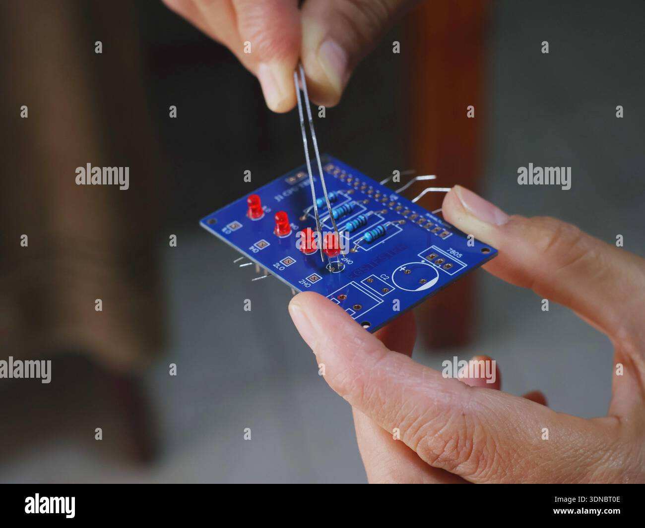 Assembling a printed circuit board using tweezers to place electronic components. Stock Photo