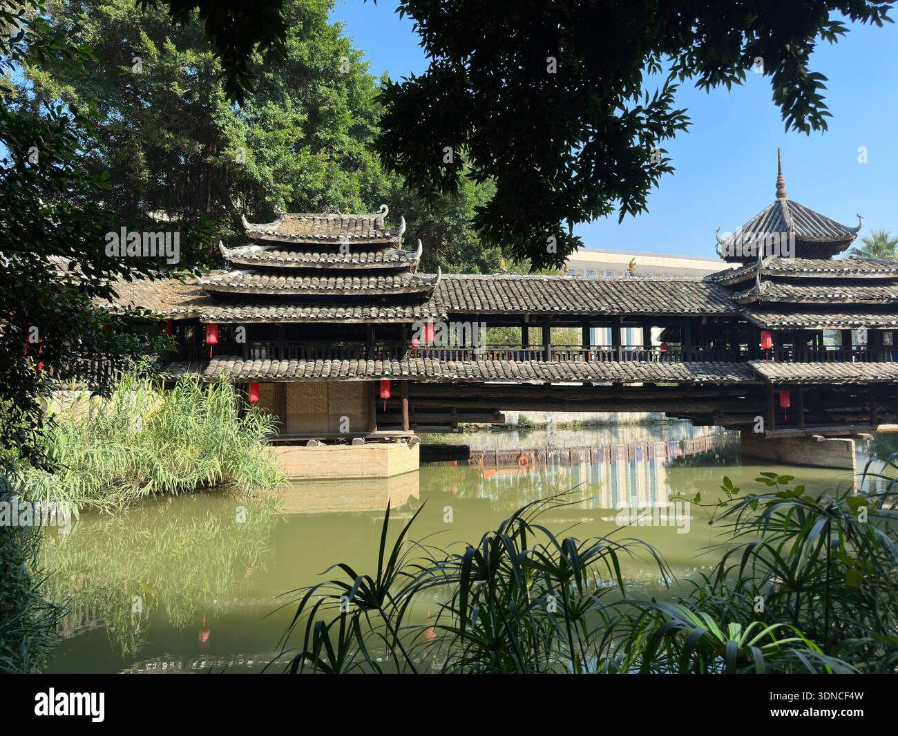 Ancient covered bridge with traditional Chinese architecture spanning a calm river in Nanning, China - Smartphone Captured Stock Image