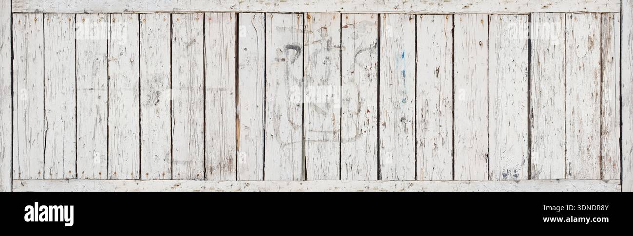A white wooden wall with many cracks, holes, showing an old, rustic, weathered surface. Aged paint, splits, imperfections create strong depth, texture Stock Photo