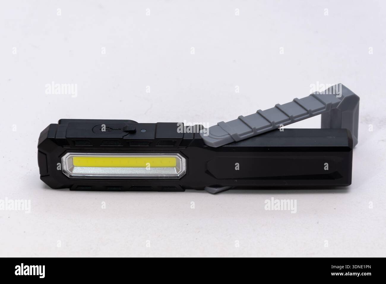 Folding work LED flashlight lies on a light isolated background Stock Photo