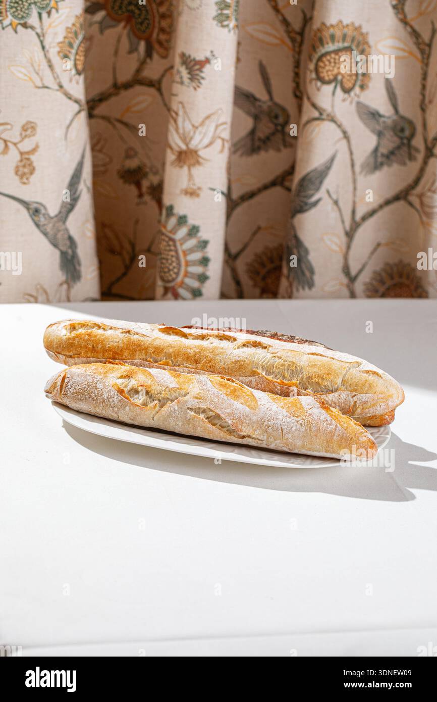 Freshly baked assorted baguettes on white plate Stock Photo