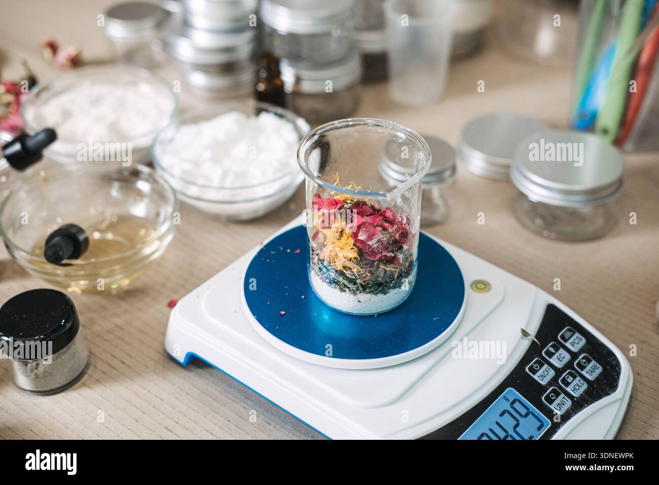Beaker filled with dried flower petals and white powder sits on digital ...