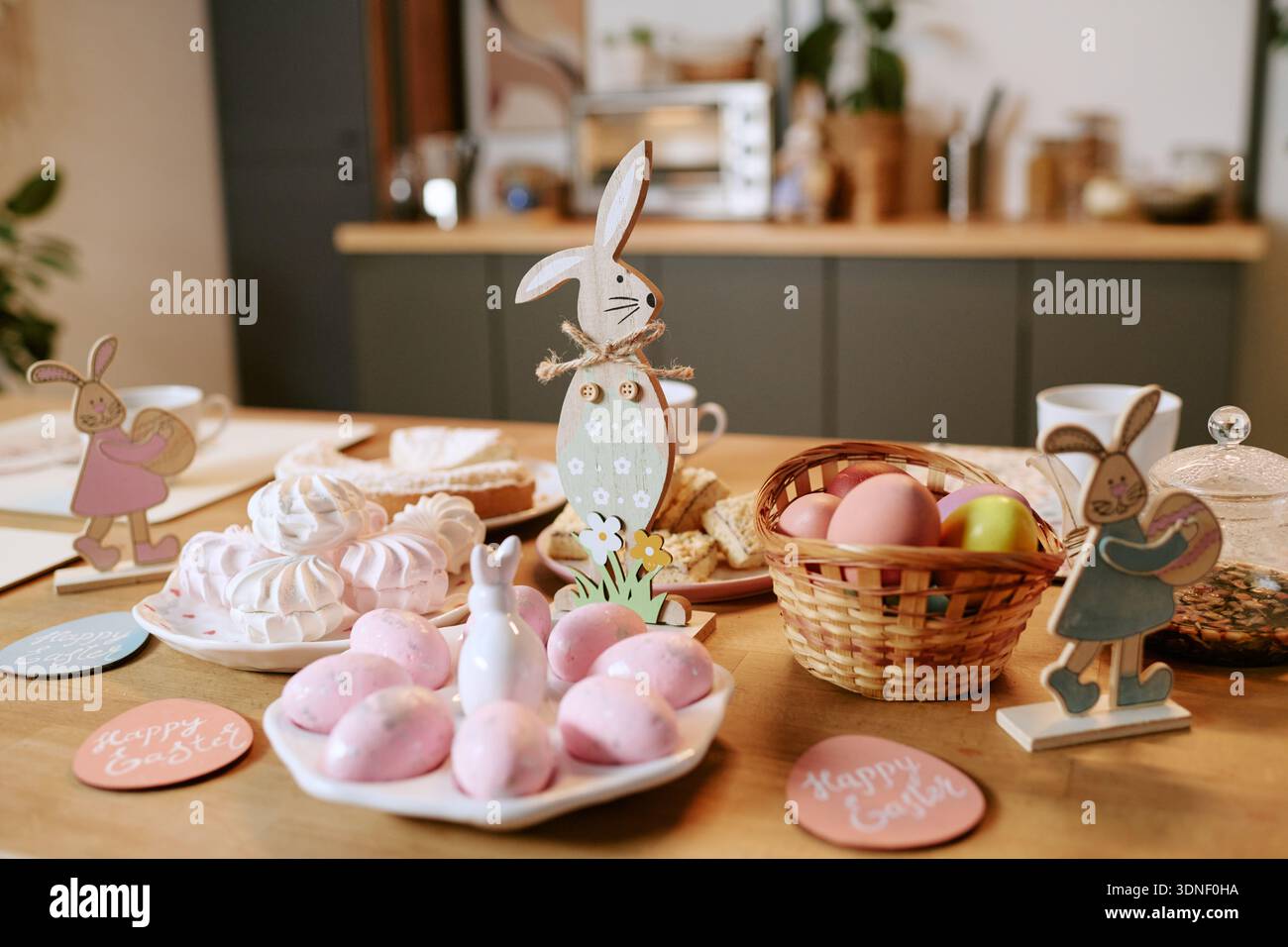 Easter Table Displaying Decorative Bunny Figures and Basket with Colored Eggs Stock Photo