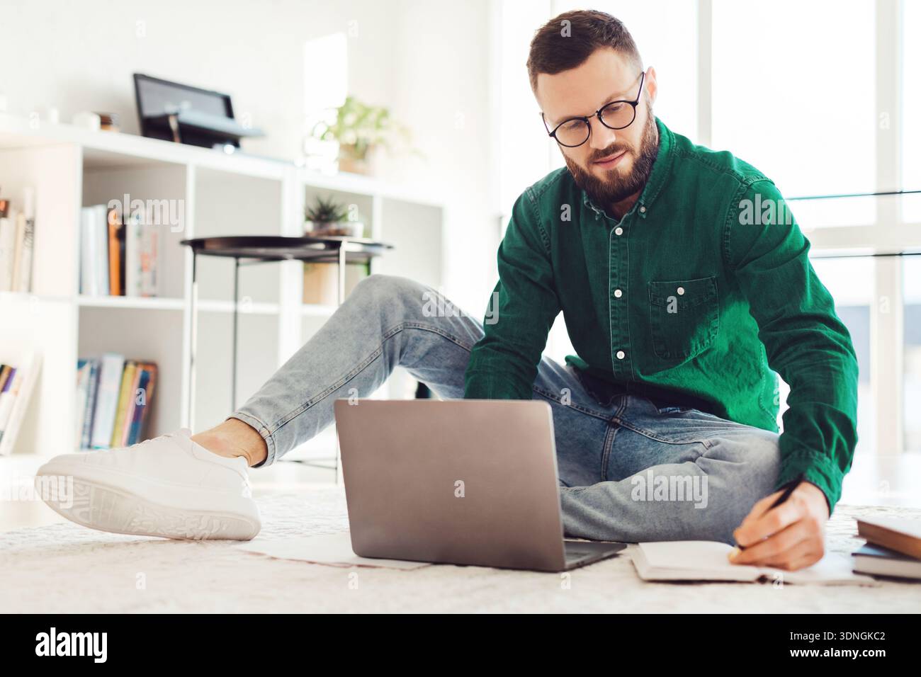 Man Taking Notes Using Laptop Sitting On Floor At Home Stock Photo