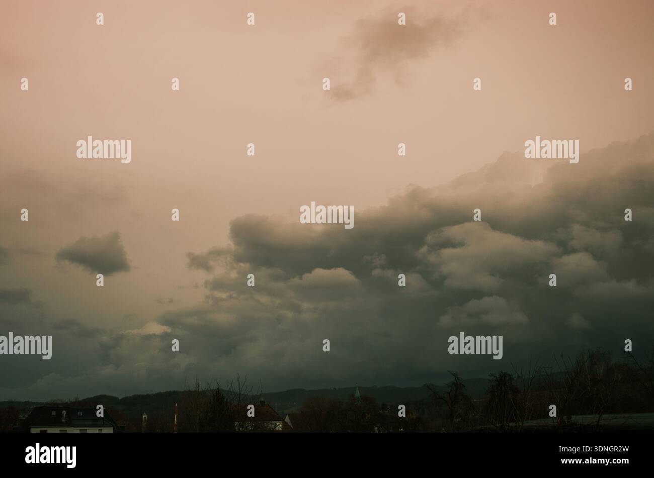 Dramatic storm clouds gather over a quiet European village at dusk Stock Photo