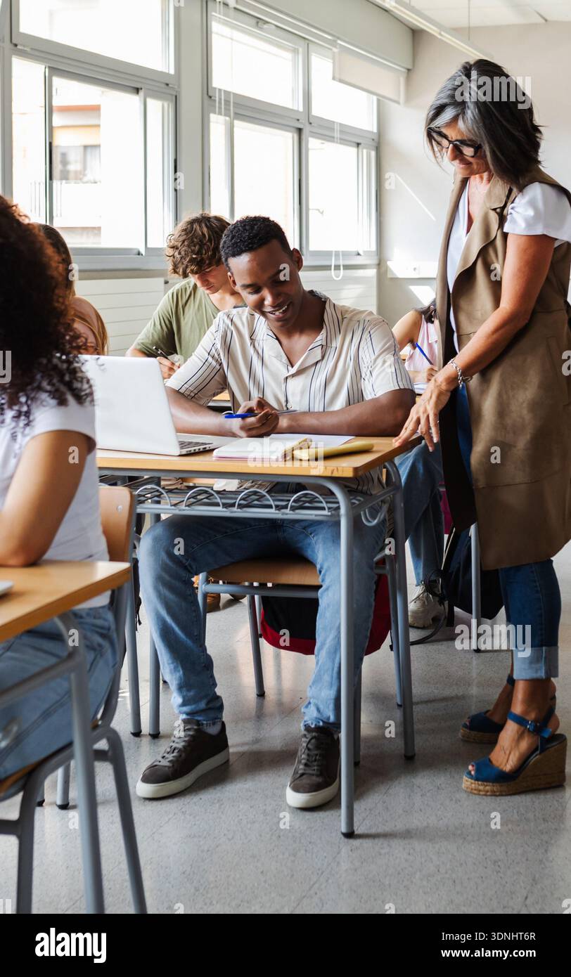 Teacher helping student with studies during classroom lesson Stock Photo