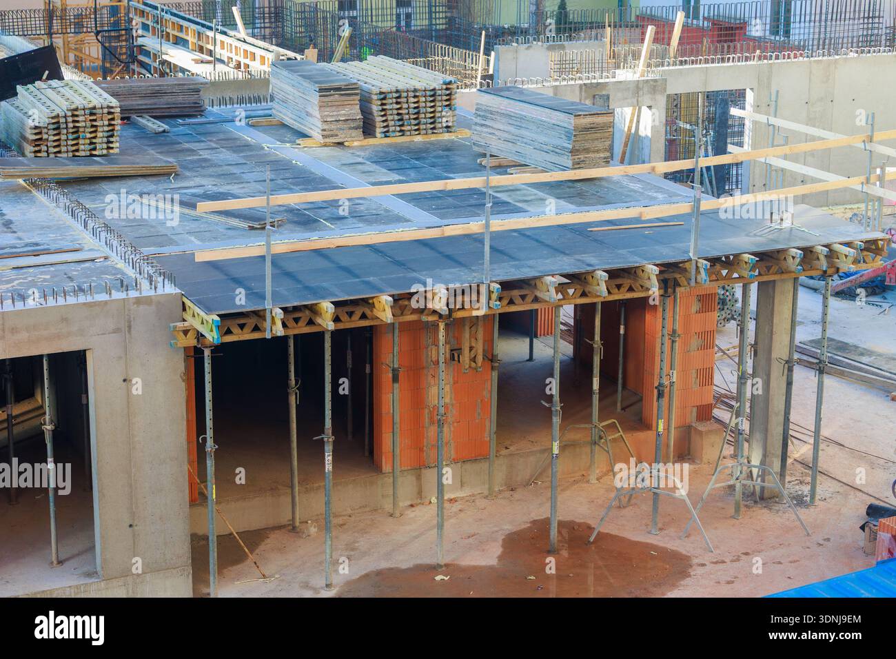 Timber Frame Rising Wall A busy construction site shows brick walls rising, timber framing, and ...
