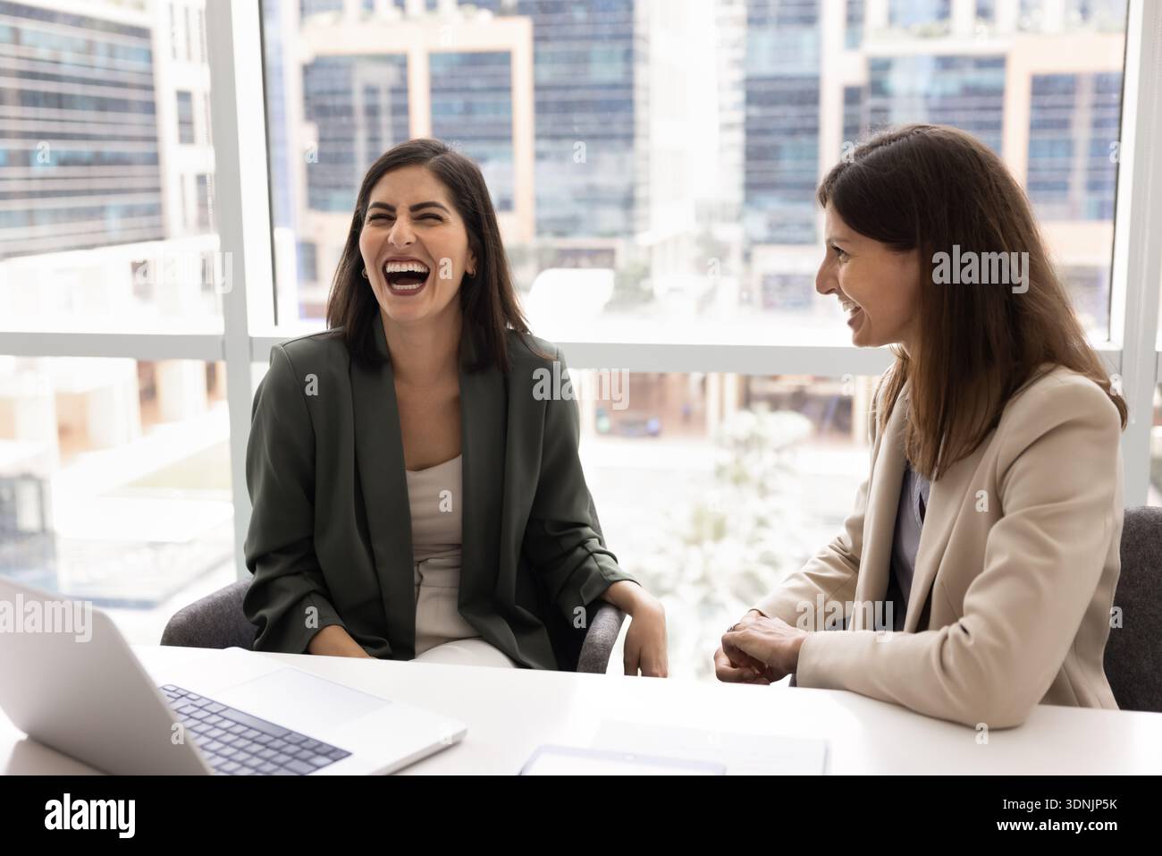 Businesswomen laughing, enjoy friendly work relations, having fun during break Stock Photo
