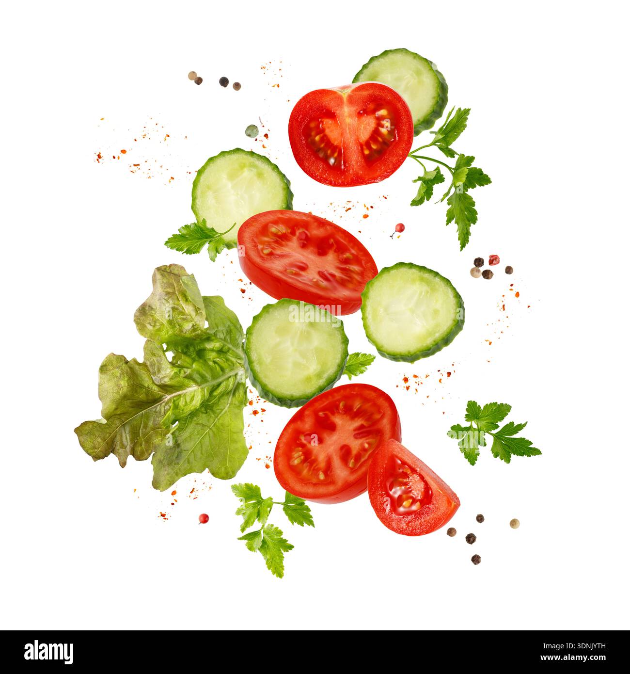 Sliced ripe juicy red tomato, cucumbers, lettuce, parsley leaves and peppers flying falling isolated on white background.  Vegetables collection Stock Photo
