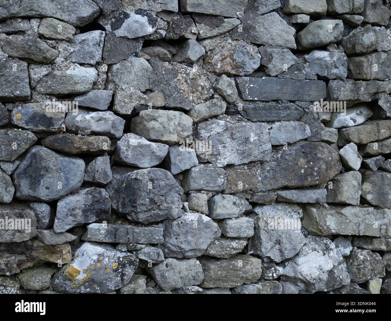 Weathered limestone dry stonewall texture with natural stone detail. Stock Photo