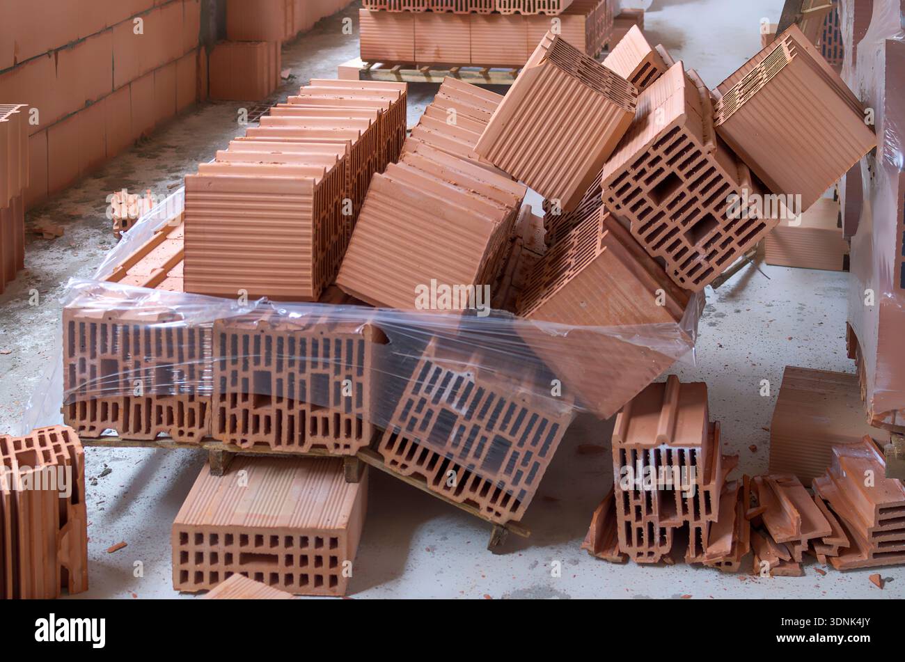Broken pallet of red clay bricks on a construction site. Collapsed building materials due to storage error or accident. Concept of workplace safety, w Stock Photo