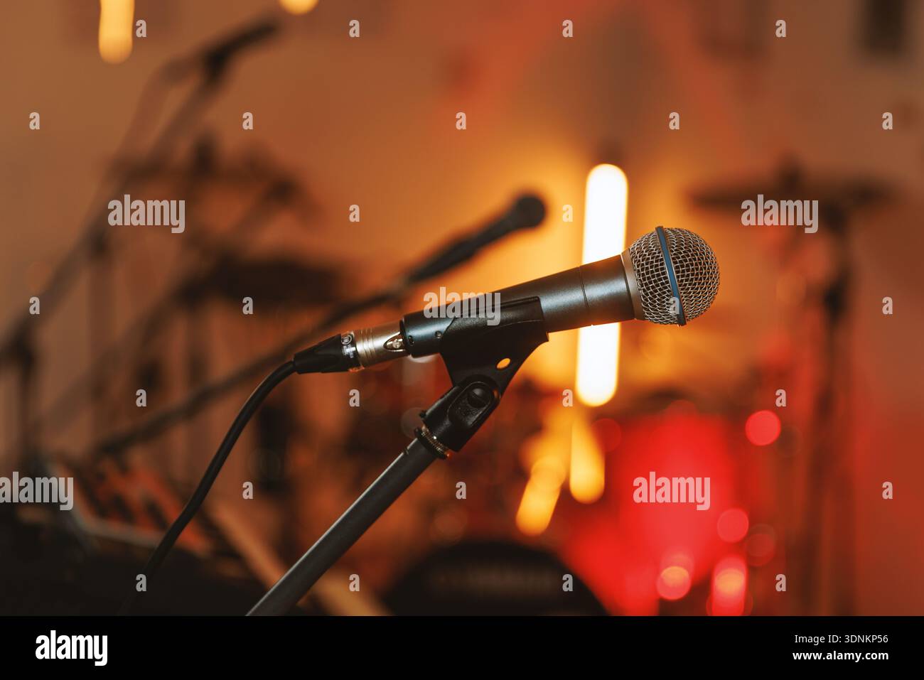 Close-up microphone on stand in warm concert lighting Stock Photo